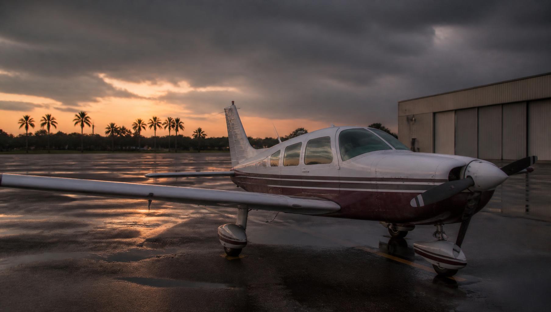 Piper PA-28 Cherokee parked on a wet ramp at dusk